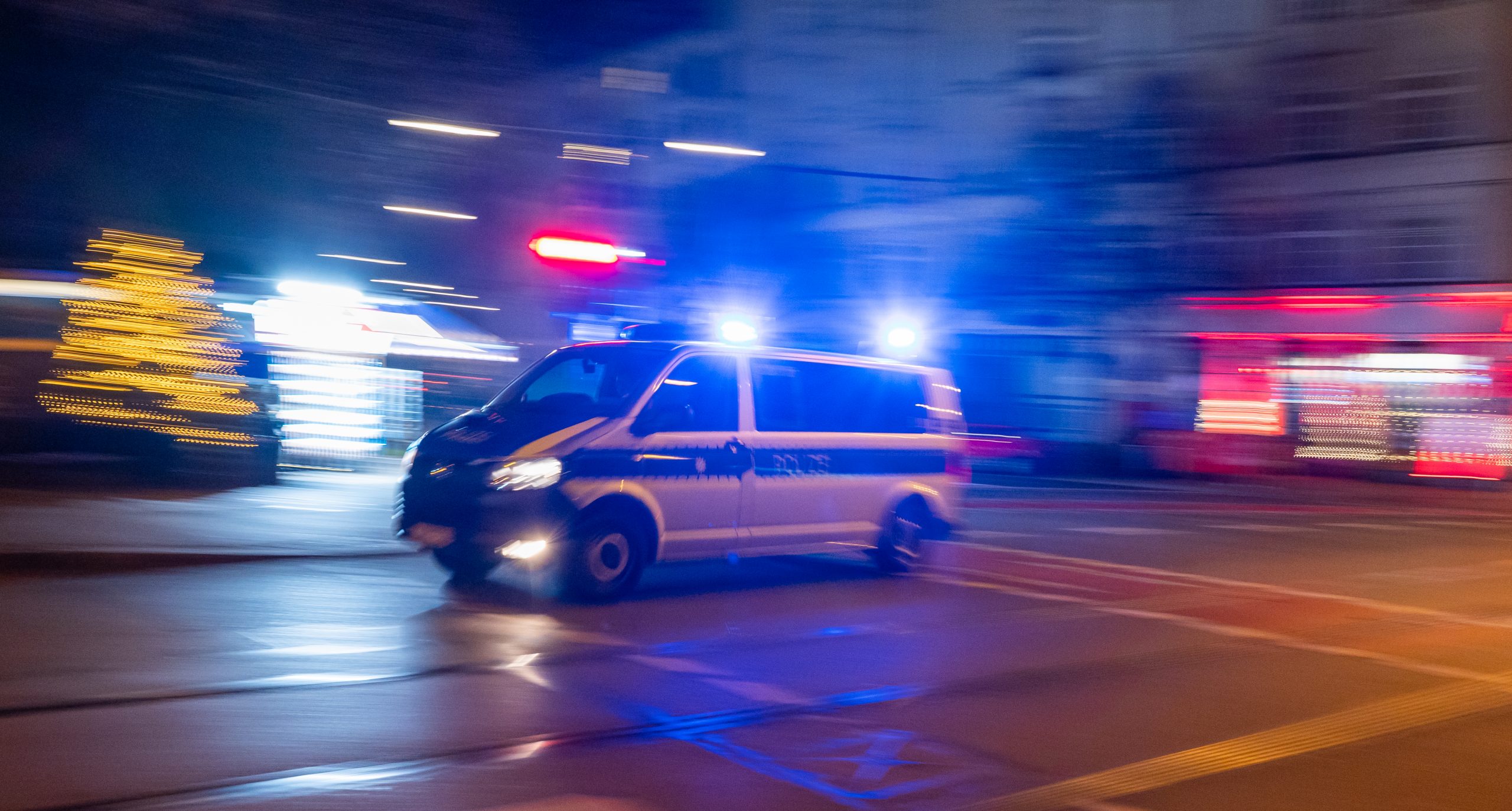 Ein Polizeifahrzeug fährt in den frühen Morgenstunden mit Blaulicht durch die Stadt.
