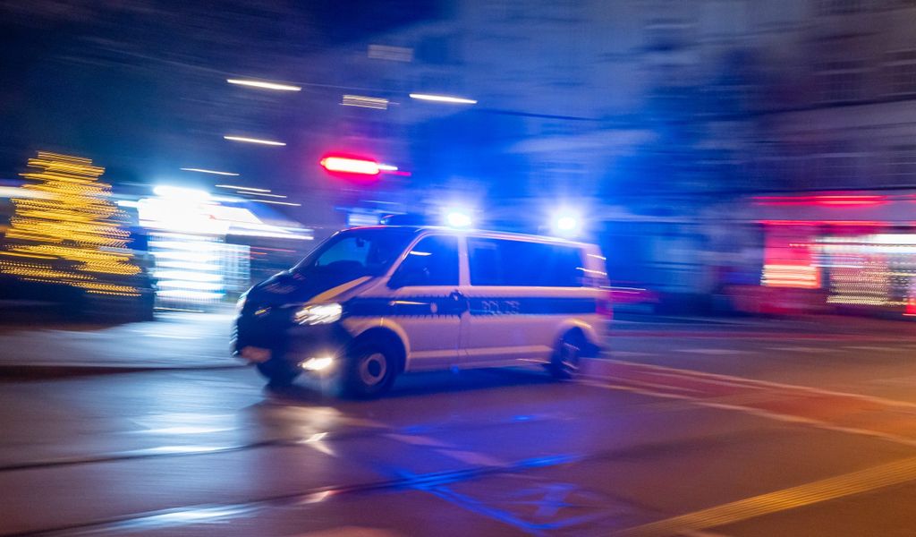 Ein Polizeifahrzeug fährt in den frühen Morgenstunden mit Blaulicht durch die Stadt.