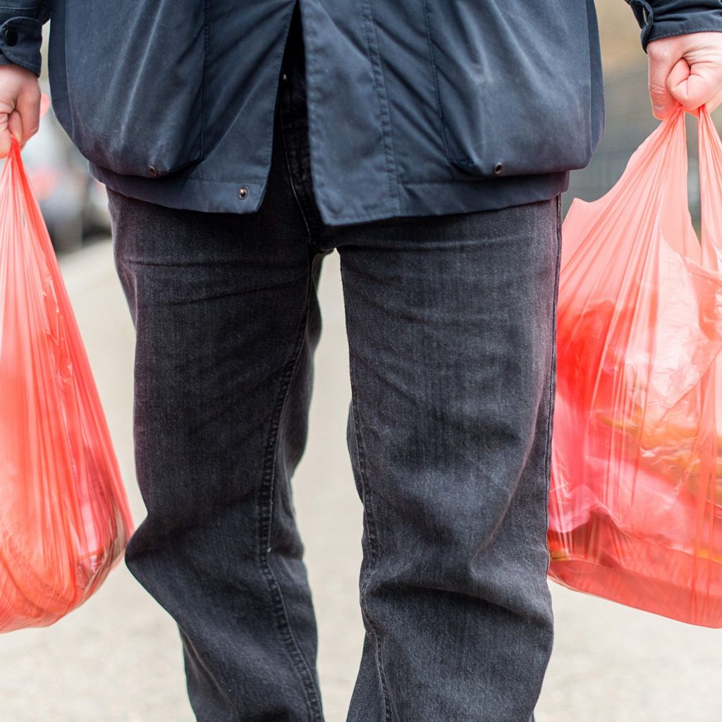 Ein Mann trägt seine Einkäufe in Plastiktüten nach Hause (Symbolbild).