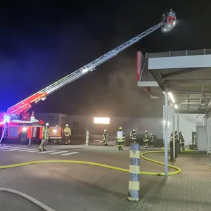 Die Feuerwehr löscht auf einer Drehleiter den Brand eines Supermarktes