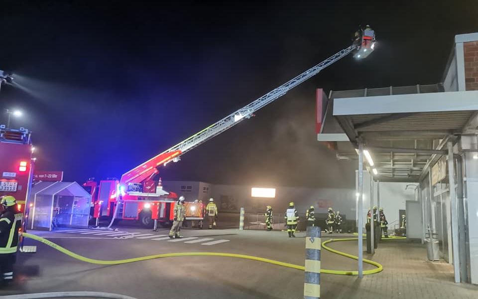 Die Feuerwehr löscht auf einer Drehleiter den Brand eines Supermarktes