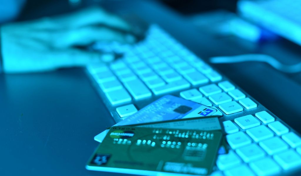 Auf einer Computertastatur liegen Kreditkarten, während eine Frau auf der Tastatur tippt.