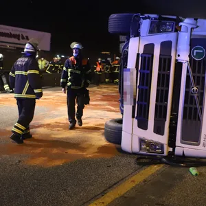 Feuerwehrleute vor dem auf die Seite gekippten Laster.