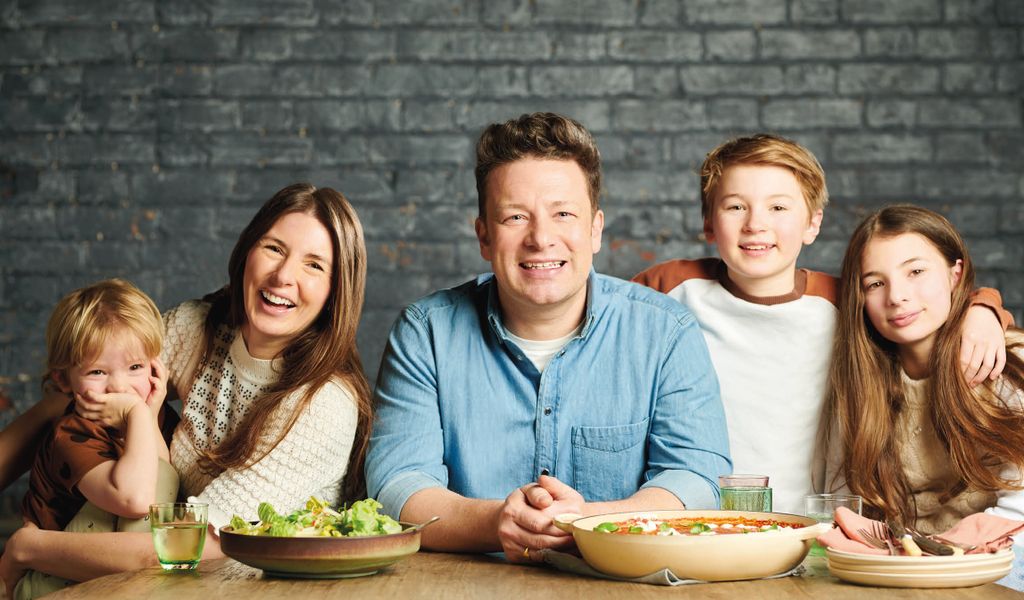 Jamie Oliver lächelt zwischen seiner Frau und drei seiner Kinder