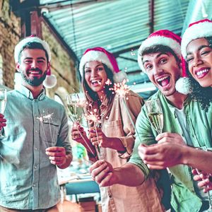 Junge Leute stoßen mit einem Glas Sekt auf Weihnachten und Silvester an