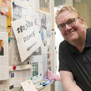 Lars Meier lehnt sich an eine Wand mit Zeitungsausschnitten