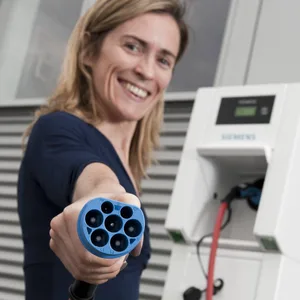 Eine Frau hält einen Ladestecker für E-Autos in der Hand.