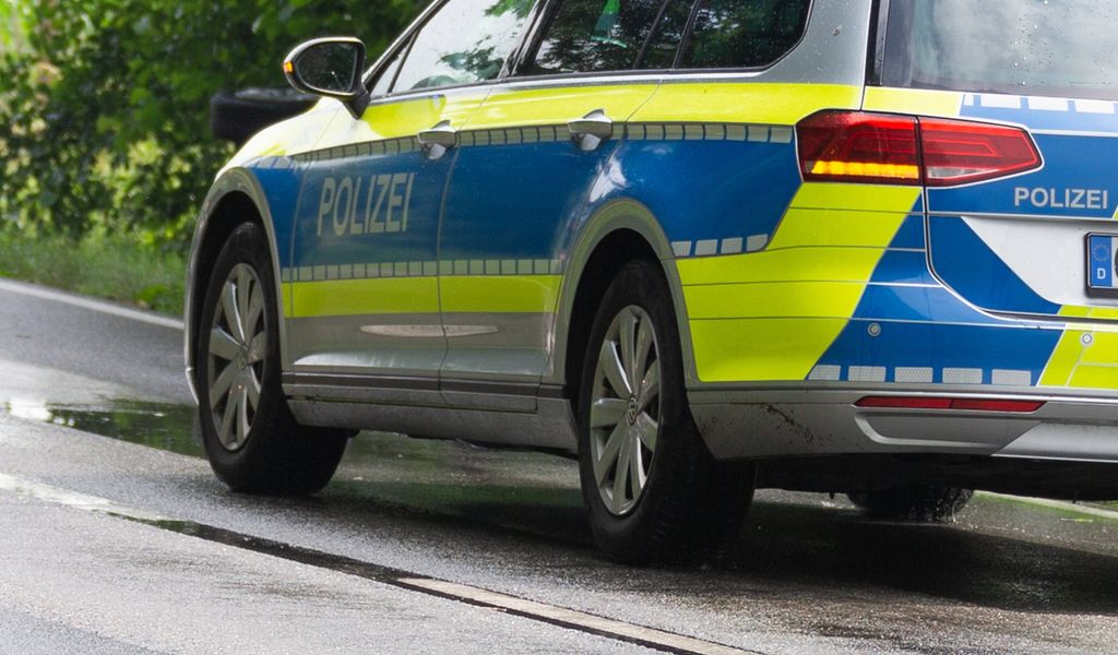 Ein Einsatzfahrzeug, Streifenwagen, der Polizei mit Schriftzug, steht auf einer regennassen Fahrbahn.
