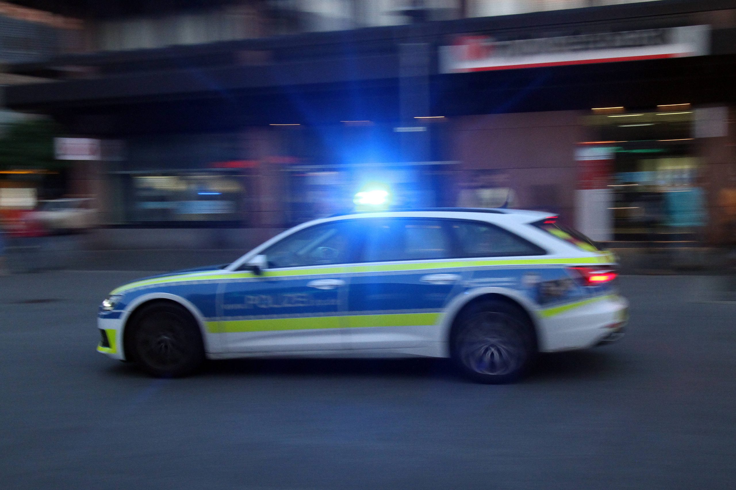 Einsatzwagen der Polizei fährt am Abend mit Blaulicht