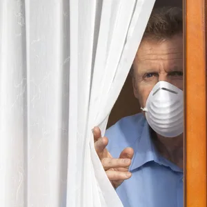 Ein Mann schaut aus dem Fenster während er in Corona-Quarantäne ist. (Symbolbild)