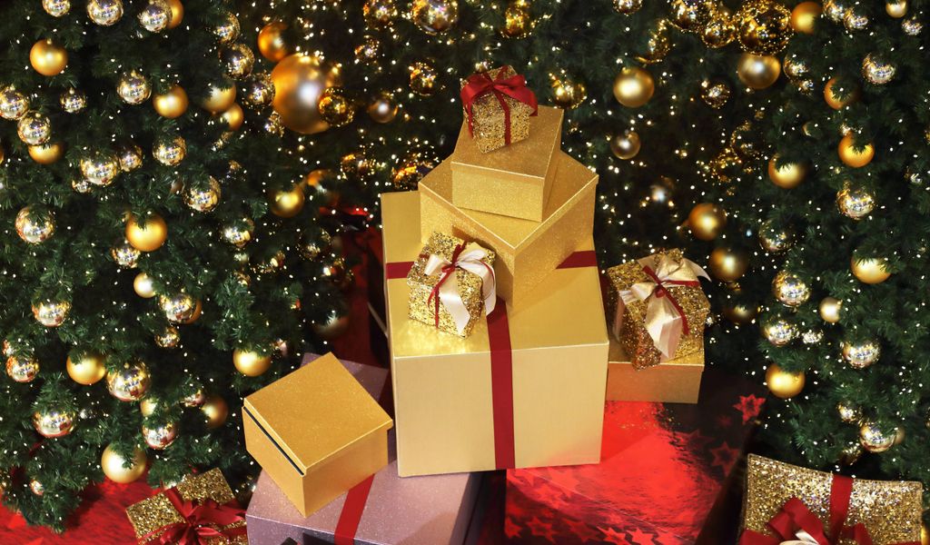 Weihnachtspäckchen vor einem Weihnachtsbaum dekoriert