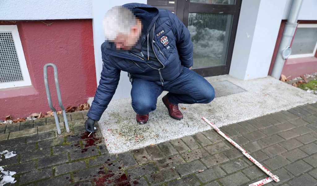 Ein Polizist untersucht die Blutlache am Tatort in Rostock.