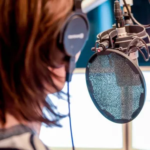 Eine Nachrichtensprecherin steht im Studio und spricht in ein Mikrofon.