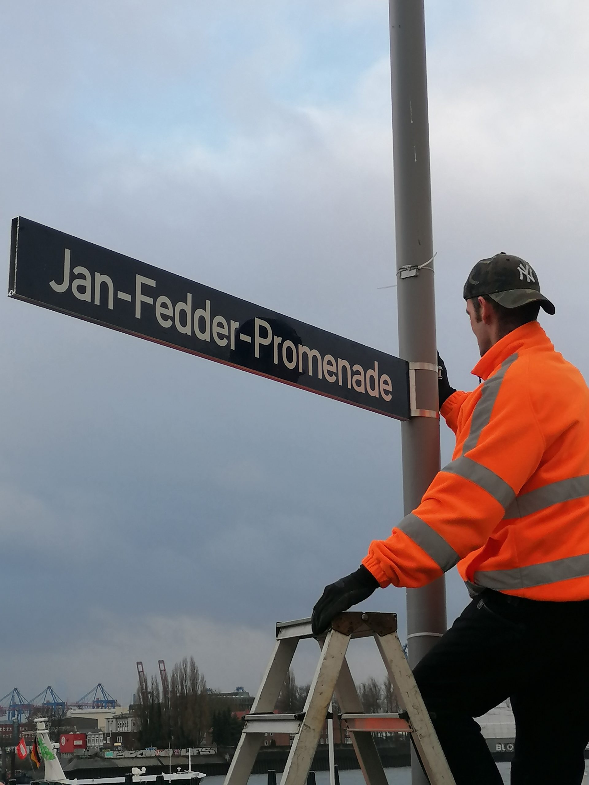 Arbeiter des Bezirksamts Mitte bringen die Schilder für die Jan-Fedder-Promenade in Hamburg an.