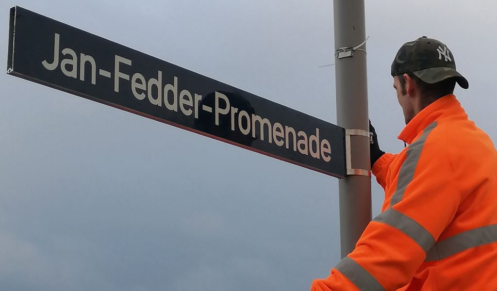 Arbeiter des Bezirksamts Mitte bringen die Schilder für die Jan-Fedder-Promenade in Hamburg an.