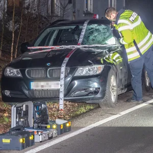 Ein Polizist untersucht den BMW. Der Fußgänger schleuderte von der Windschutz auf den Asphalt zurück.