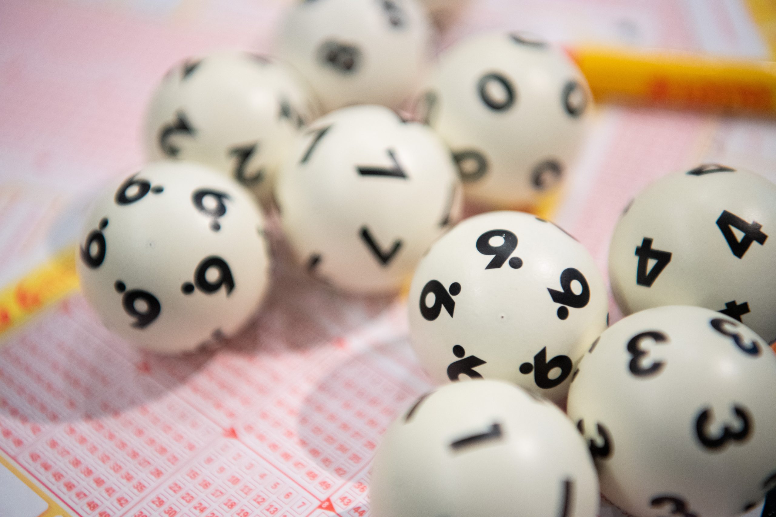 Lottokugeln liegen auf einem Lottoschein