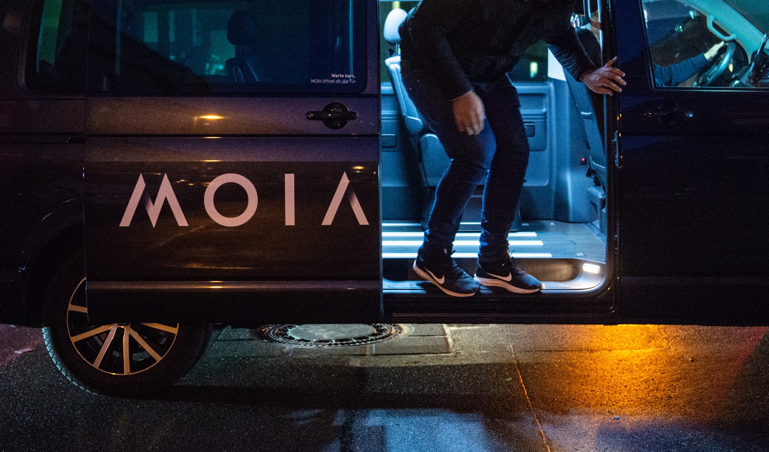 Ein Fahrgast des Ridesharing Anbieters MOIA steigt nach der Fahrt aus dem VW-Bus aus.