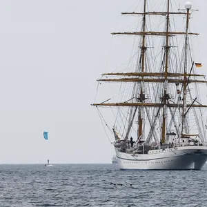 Begleitet von Kitesurfern fährt die „Gorch Fock“ am Ostseebad Laboe vorbei.