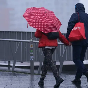 Passanten gehen im Regen an den Landungsbrücken auf der Elbpromenade spazieren.