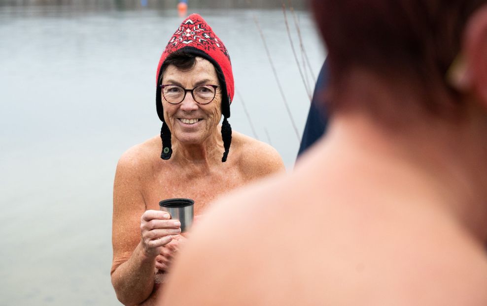 Ein Frau steht mit einem warmen Punsch beim 7. Neujahrs-Nackt-Schwimmen am Sonnensee. 