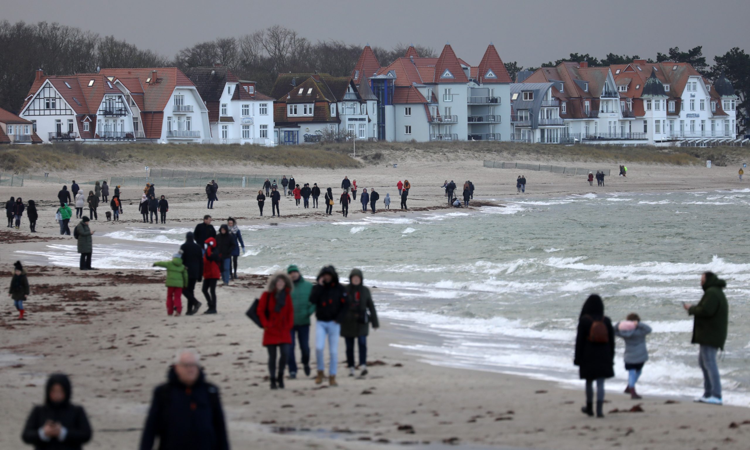 Spaziergänger sind am Strand von Warnemünde unterwegs.