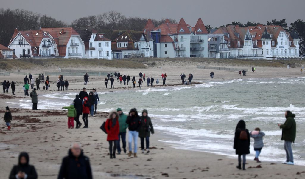 Spaziergänger sind am Strand von Warnemünde unterwegs.