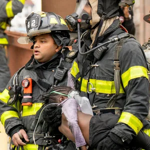 Feuerwehrleute tragen Kinder aus einem Wohnhaus in der Bronx.