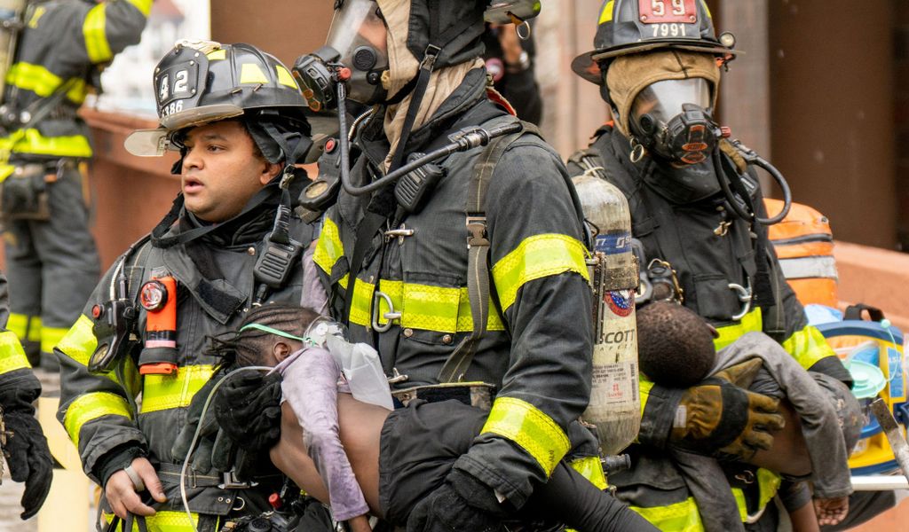 Feuerwehrleute tragen Kinder aus einem Wohnhaus in der Bronx.