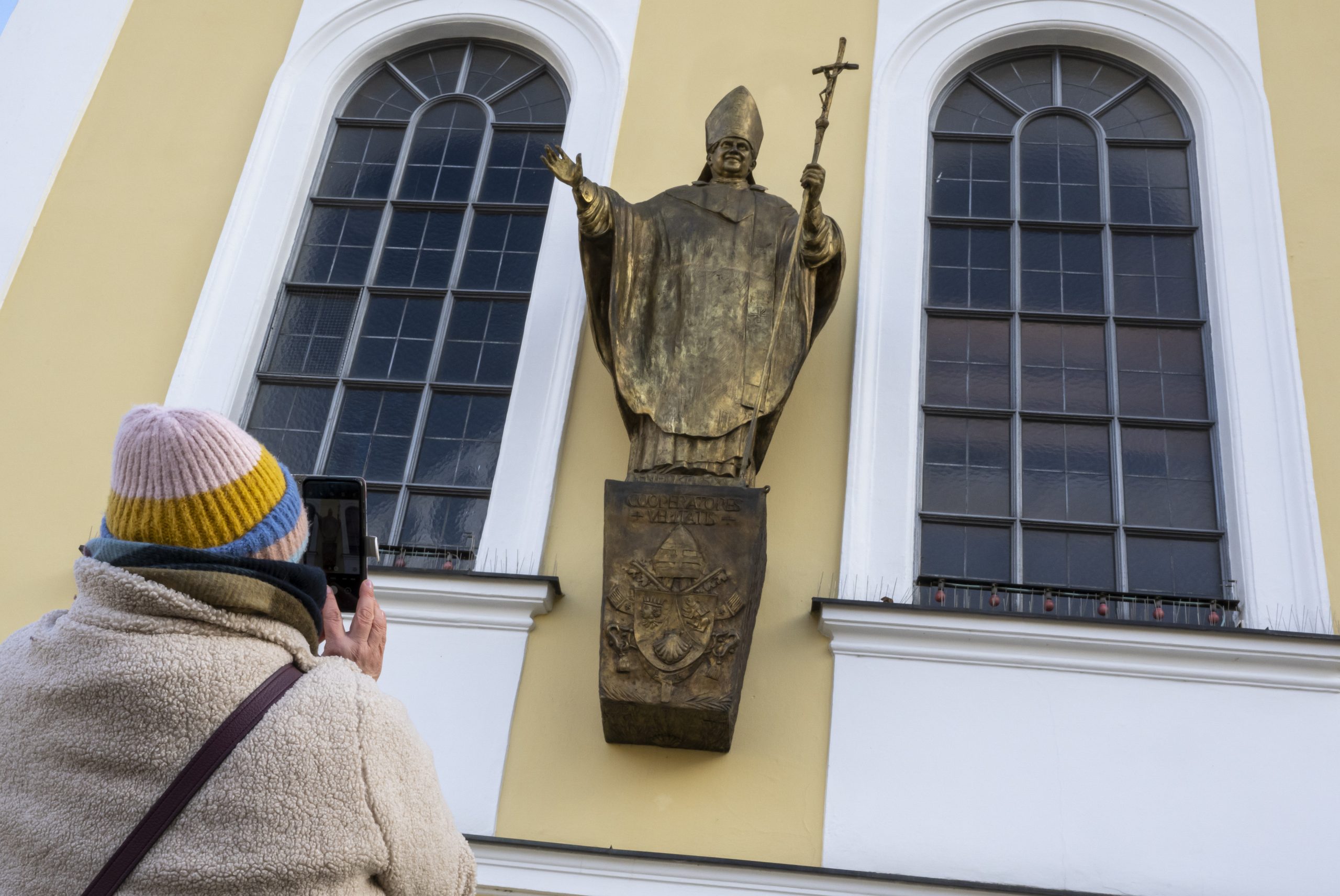 Eine Figur des emeritierten Papstes Benedikt XVI. hängt an einer Fassade am Kapellenplatz im Zentrum von Altötting.