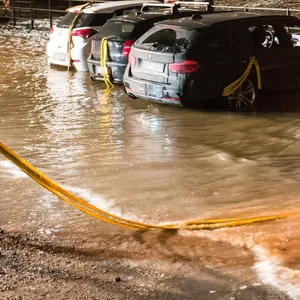 Autos stehen während einer Sturmflut im Wasser der Elbe auf einem Parkplatz in der HafenCity und werden von einem Feuerwehrmann gesichert.