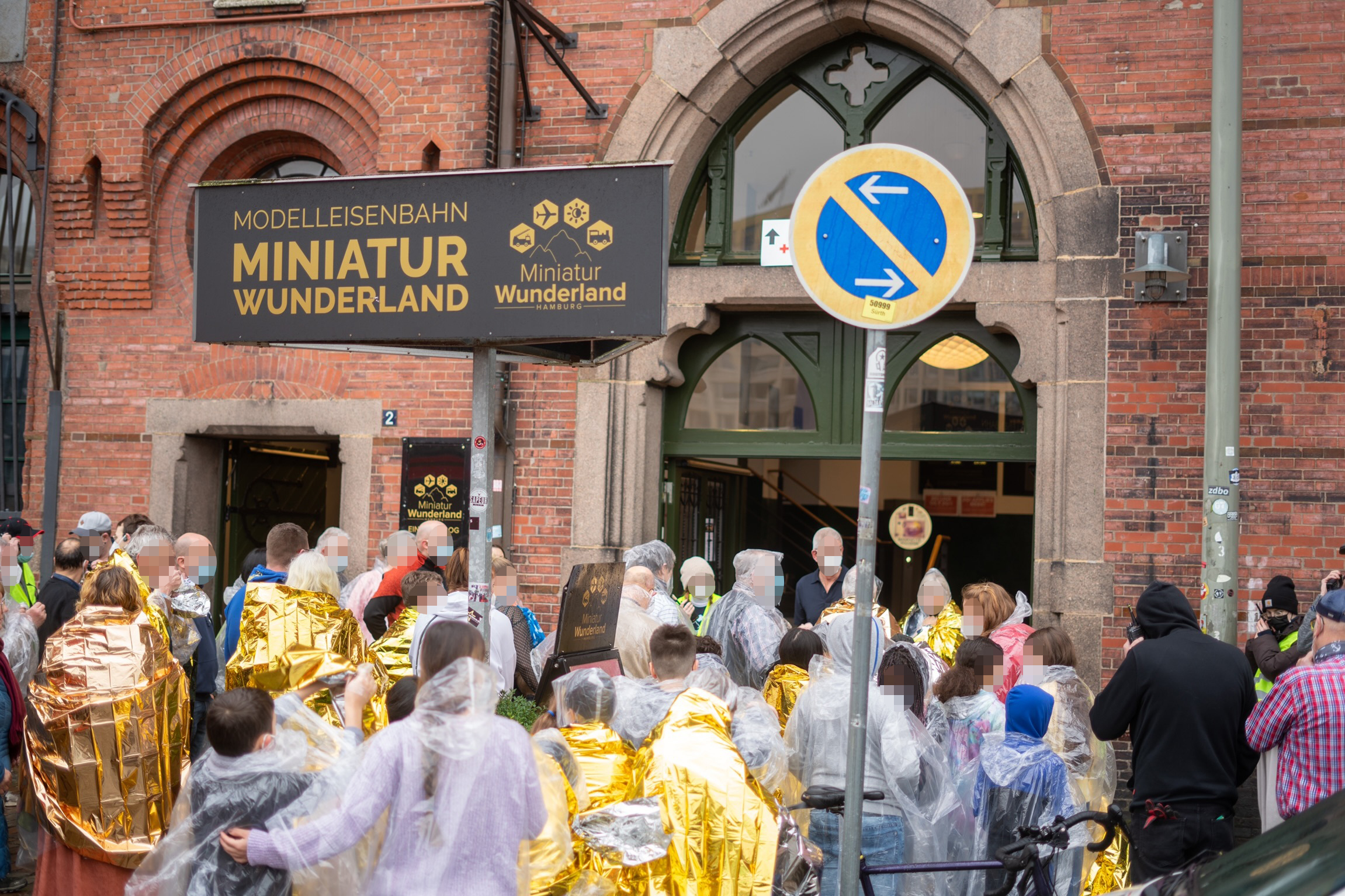 Besucher des Miniatur Wunderlandes stehen in Regencapes und Heizdecken vor dem Eingang