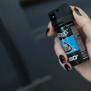 Eine Frau hält Pfefferspray in den Händen.