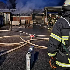 Feuerwehrkräfte vor dem Lager, in dem ein Brand ausbrach.