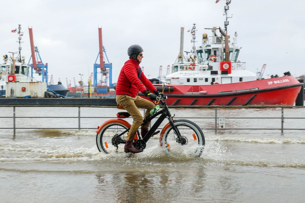 Ein Fahrradfahrer trotzt dem Hochwasser in Hamburg.