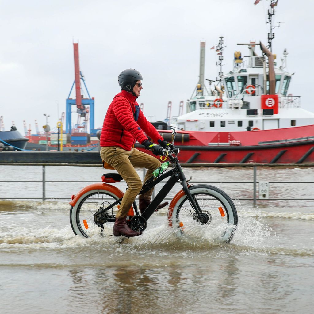 Ein Fahrradfahrer trotzt dem Hochwasser in Hamburg.