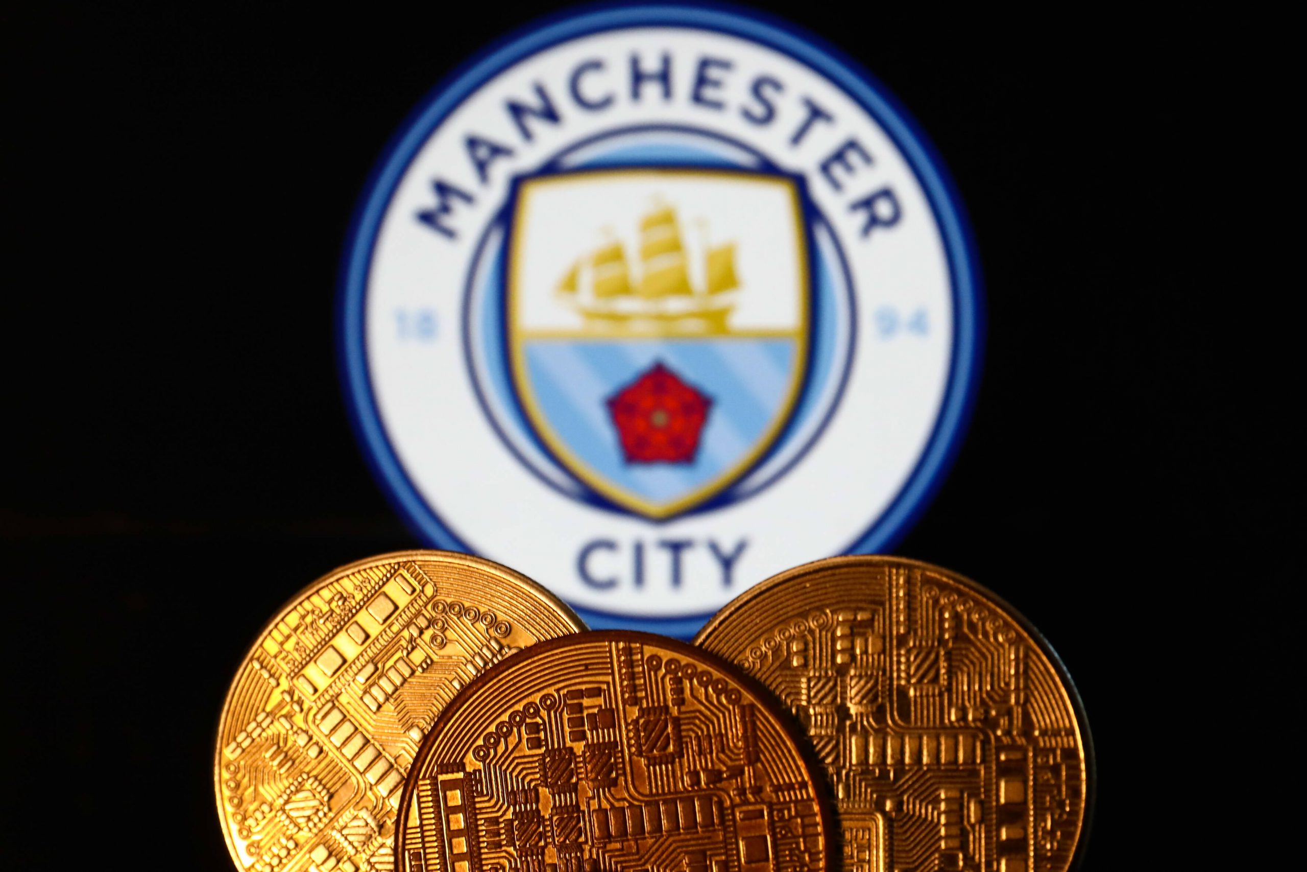 Manchester City Logo über Goldmünzen.