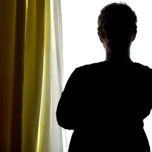 Eine junge Frau steht in einem Zimmer eines Frauenhauses. (Symbolbild)