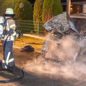 Feuerwehrkräfte vor dem ausgebrannten VW in Wintermoor-Geversdorf