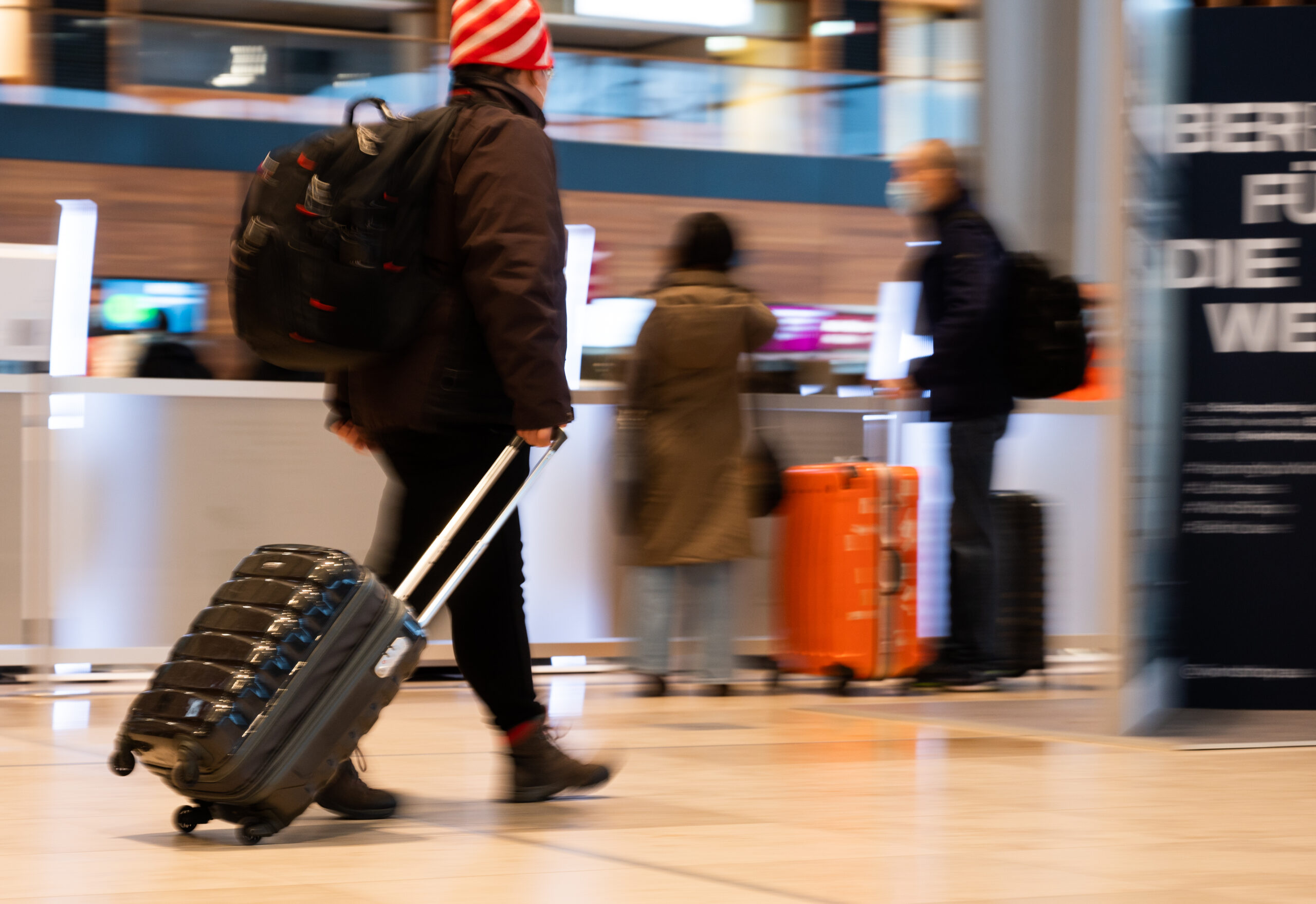 Menschen gehen im Terminal 1 am Flughafen Berlin Brandenburg durch die Haupthalle.