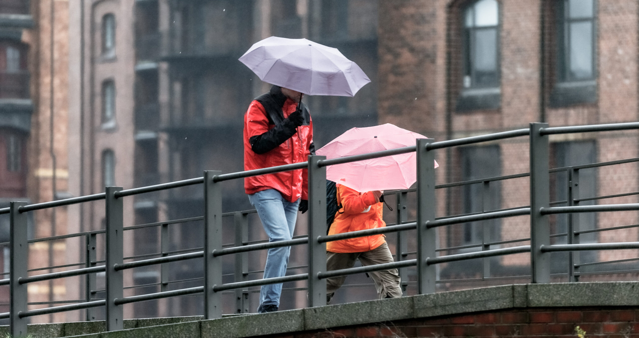 Zwei Menschen mit Regenschirmen in der Speicherstadt.