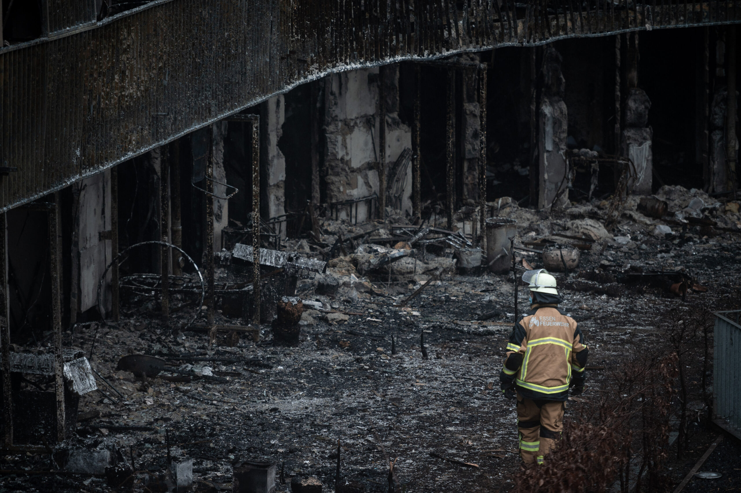 Ein Feuerwehrmann geht durch die verbrannten Gärten des Wohnkomplex.