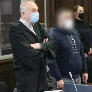 Einer der beiden Angeklagten wartet mit seinem Anwalt in einem Gerichtssaal des Strafjustizgebäudes in Hamburg auf den Prozessbeginn.