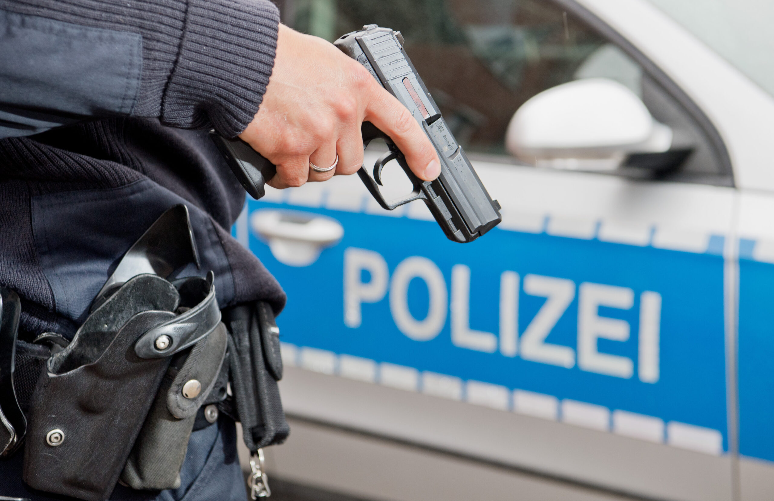 Ein Polizist hält seine Dienstwaffe in der Hand
