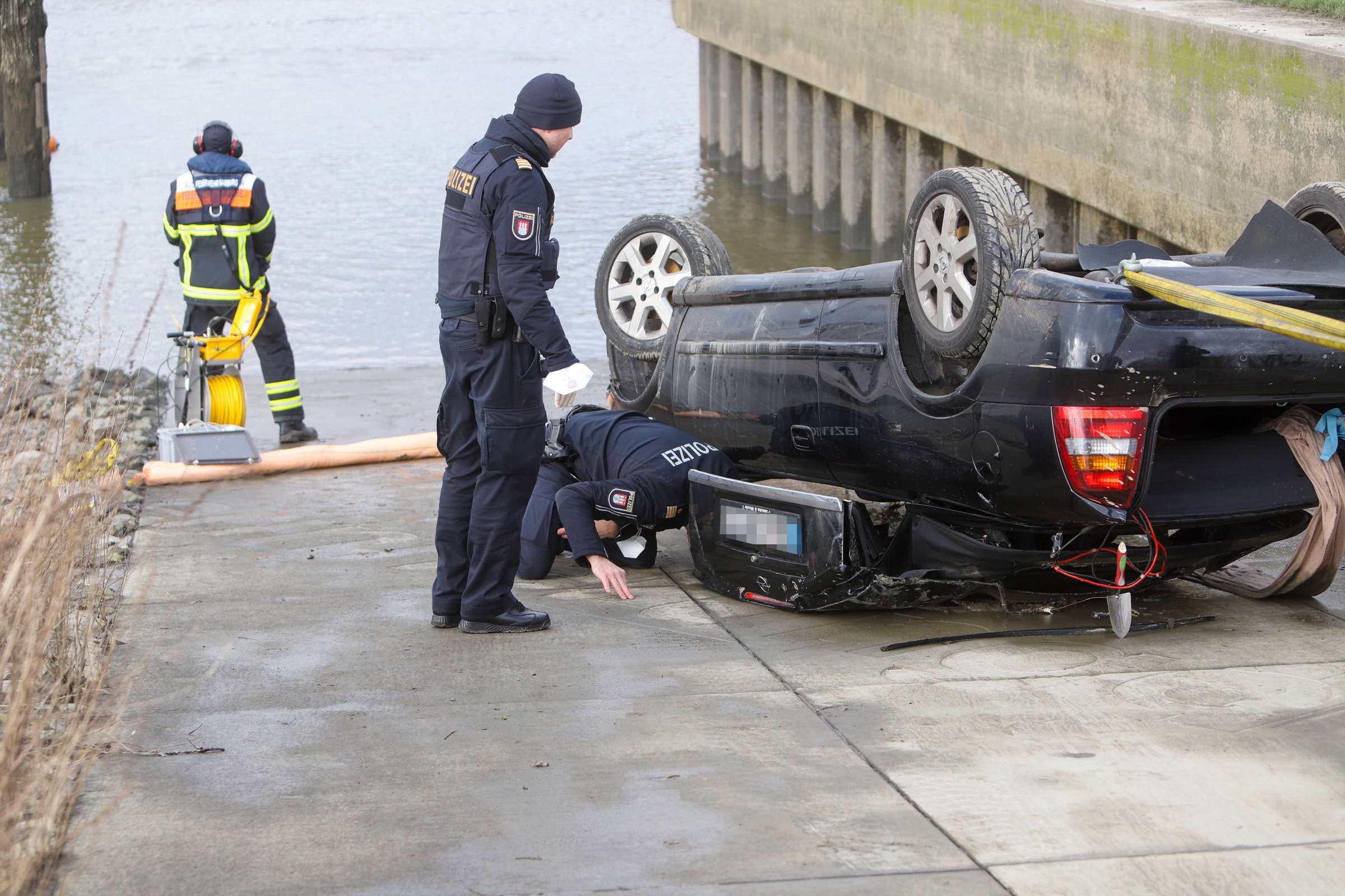 Die Beamten untersuchen das Auto, nachdem es aus dem Wasser gezogen wurde.