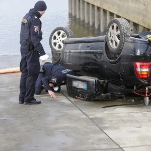 Die Beamten untersuchen das Auto, nachdem es aus dem Wasser gezogen wurde.