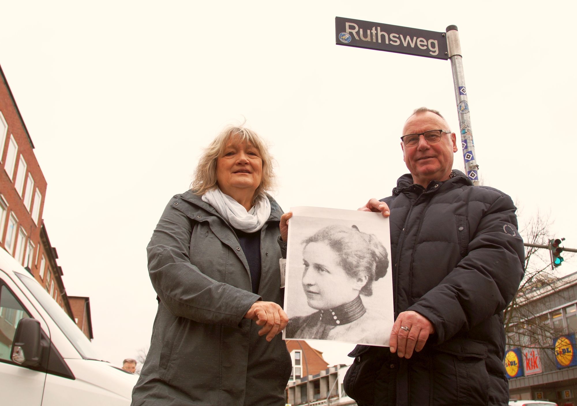 Beate Seelis (Grüne) und Rüdiger Wendt (SPD) mit einem Foto von Amelie Ruths am Ruthsweg in Barmbek.
