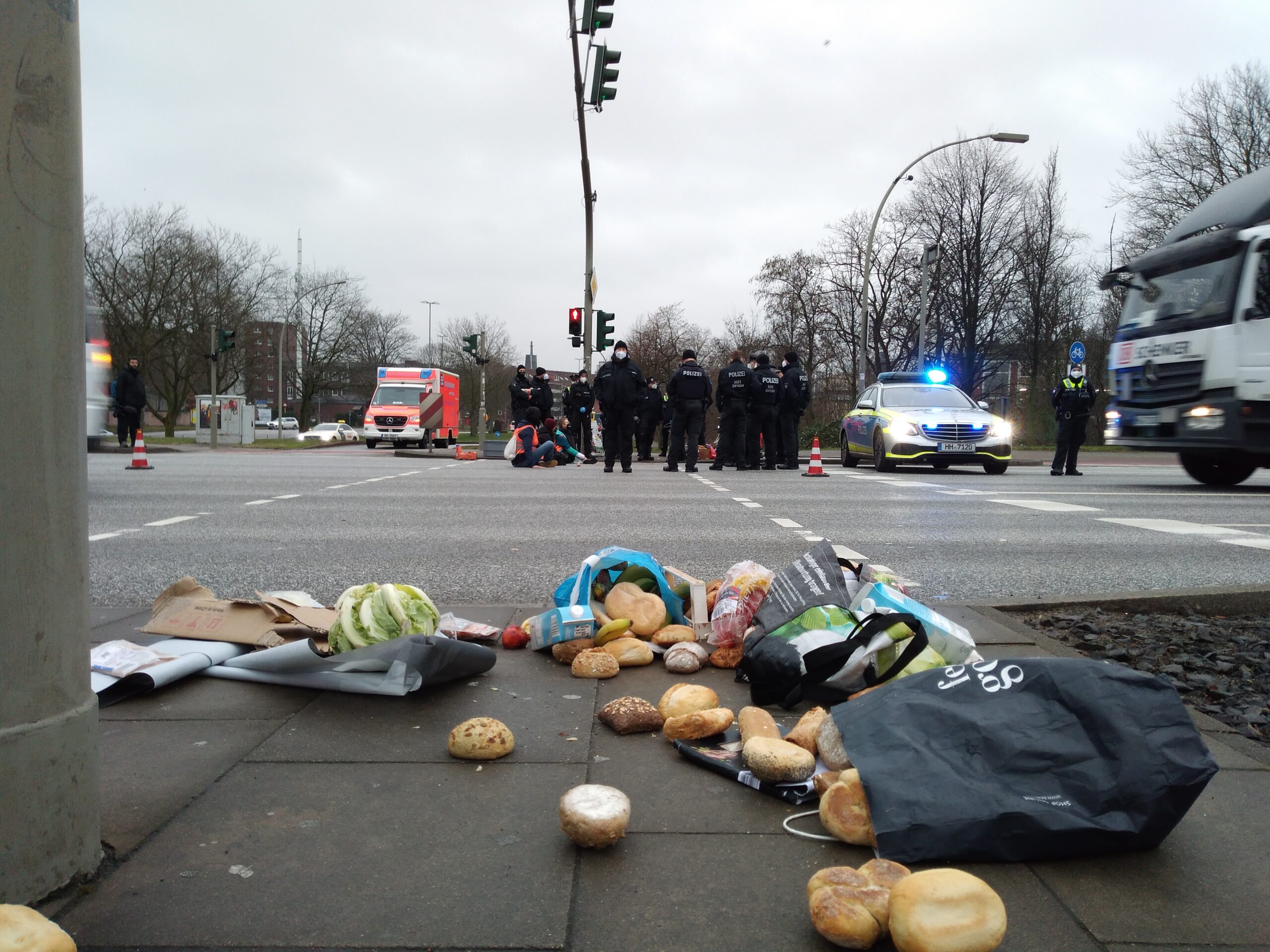 Brötchen liegen auf dem Bürgersteig verstreut, Polizisten stehen um eine Gruppe Aktivisten