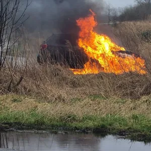 An einem Feldweg steht ein Kleinwagen in Flammen
