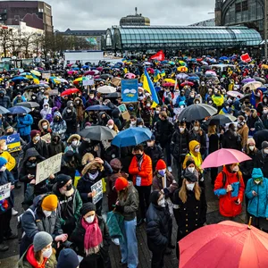 Vor dem Hauptbahnhof stehen zahlreiche Menschen und halten Ukraine-Flaggen hoch